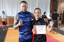 Elisa Dill, estudante da UNILA, com seu Mestre Anderson Torres, recebendo a certificação de faixa vermelha de Kung Fu