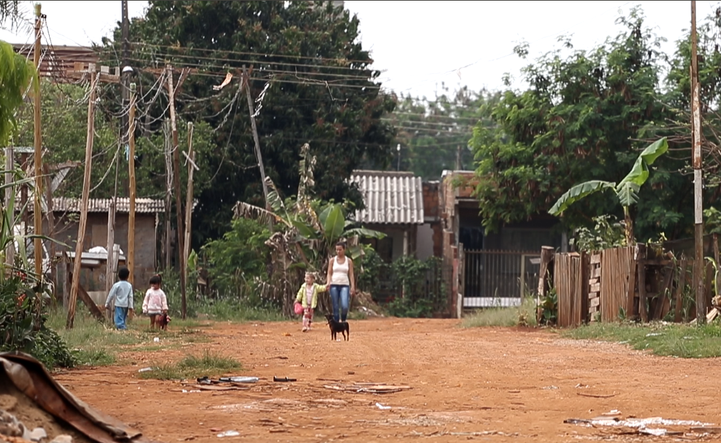 Mulher e criança caminham em estrada de terra na ocupação do Bubas