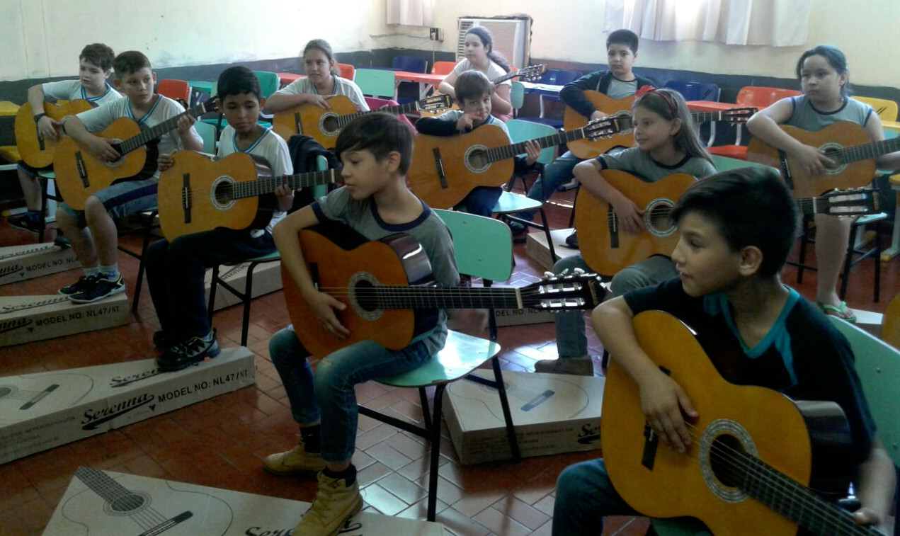 Crianças em sala de aula, aprendendo a tocar violão