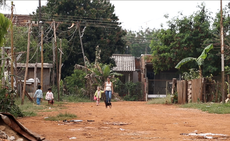 Mulher e criança caminham de mãos dadas em rua de terra na Ocupação do Bubas