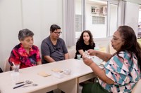 Graduada em Psicologia, a residente Vitória [na cabeceira, ao lado dos atendidos] atende crianças e idosos