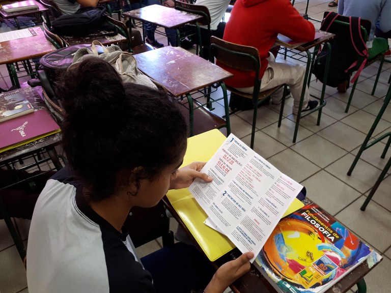 Estudante lê folheto distribuído durante apresentação do projeto Unila ao seu Alcance